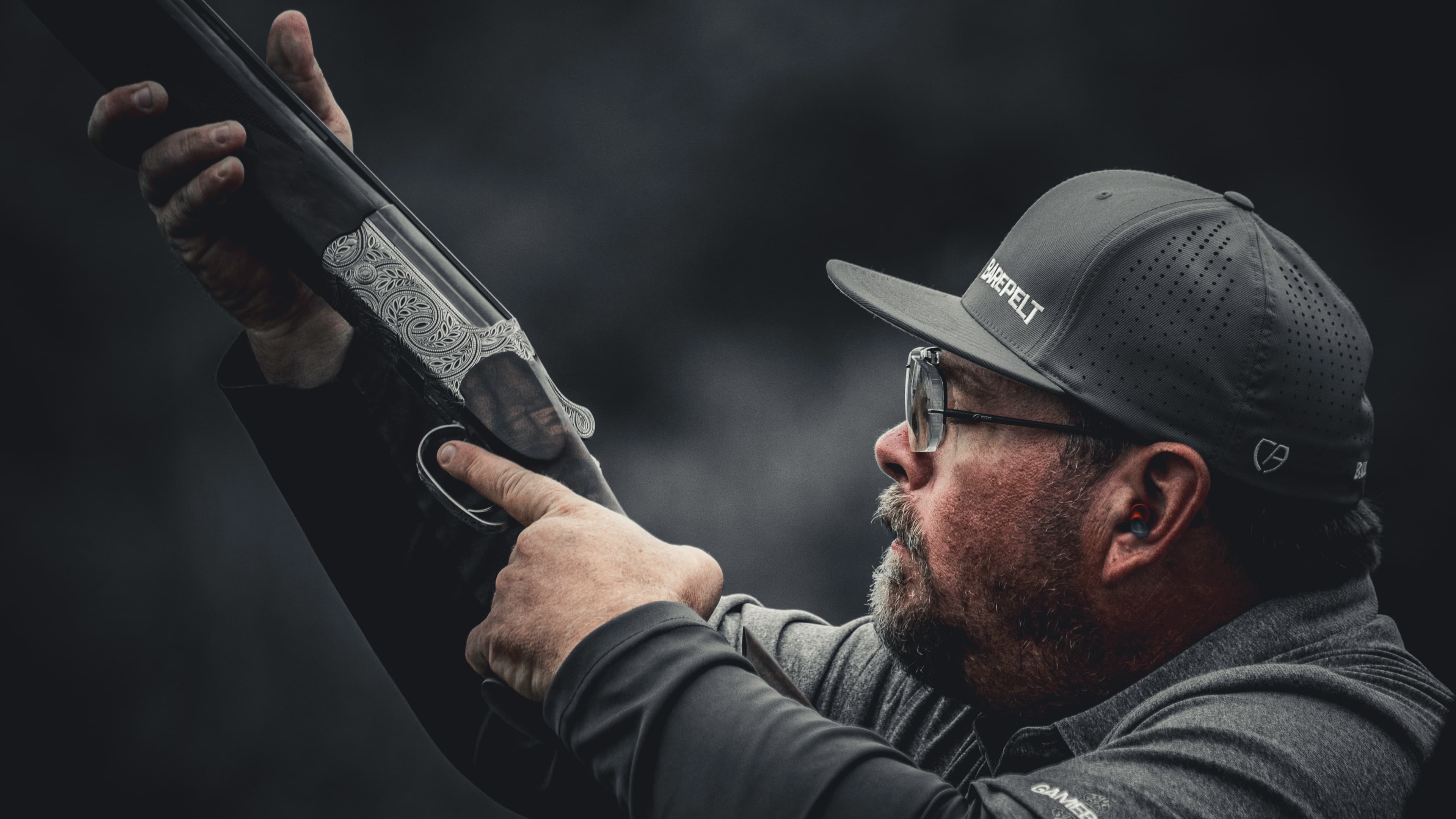 Close detail of a shooter checking a shotgun in low light.
