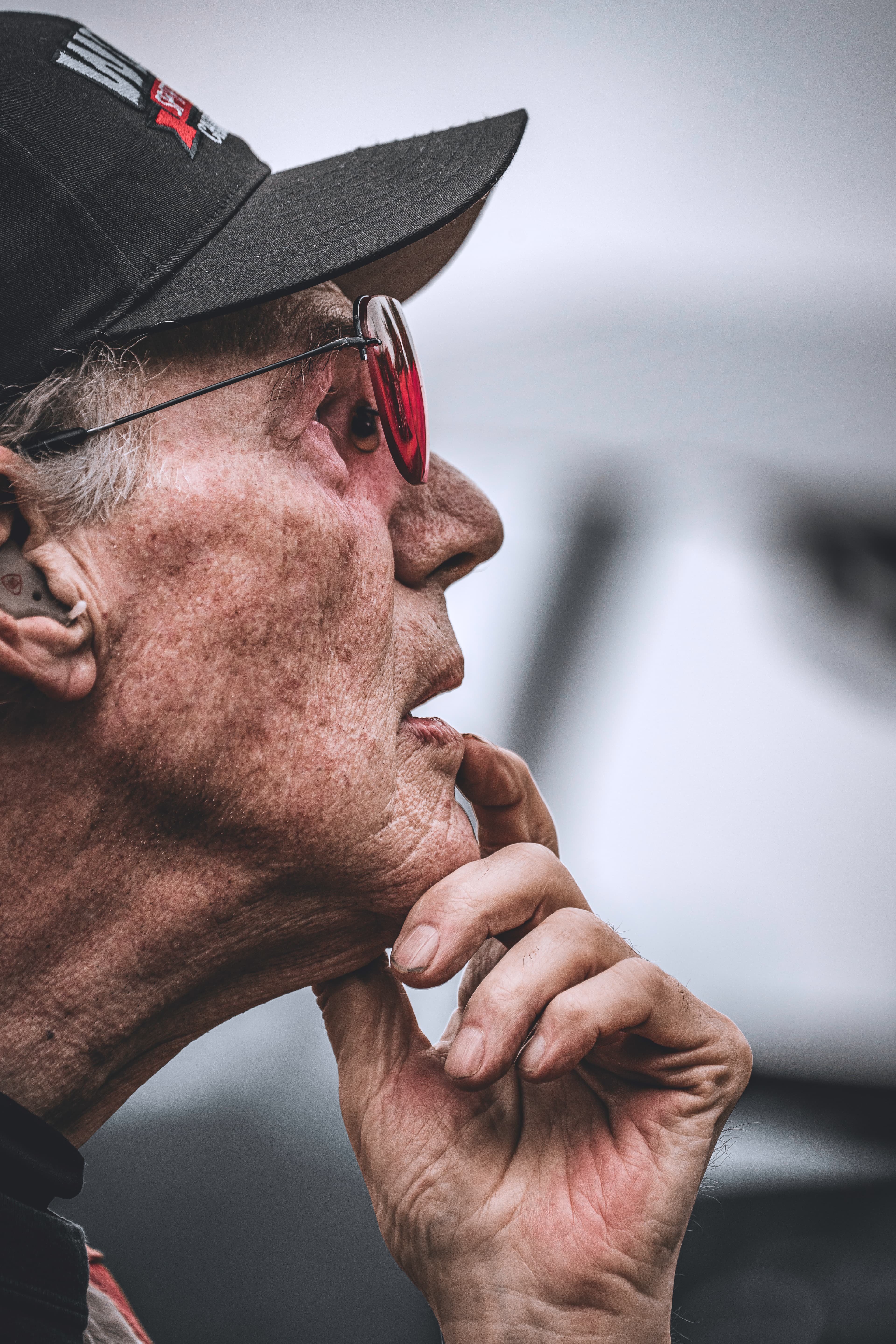 A close profile of a person looking outward through tinted shooting glasses.