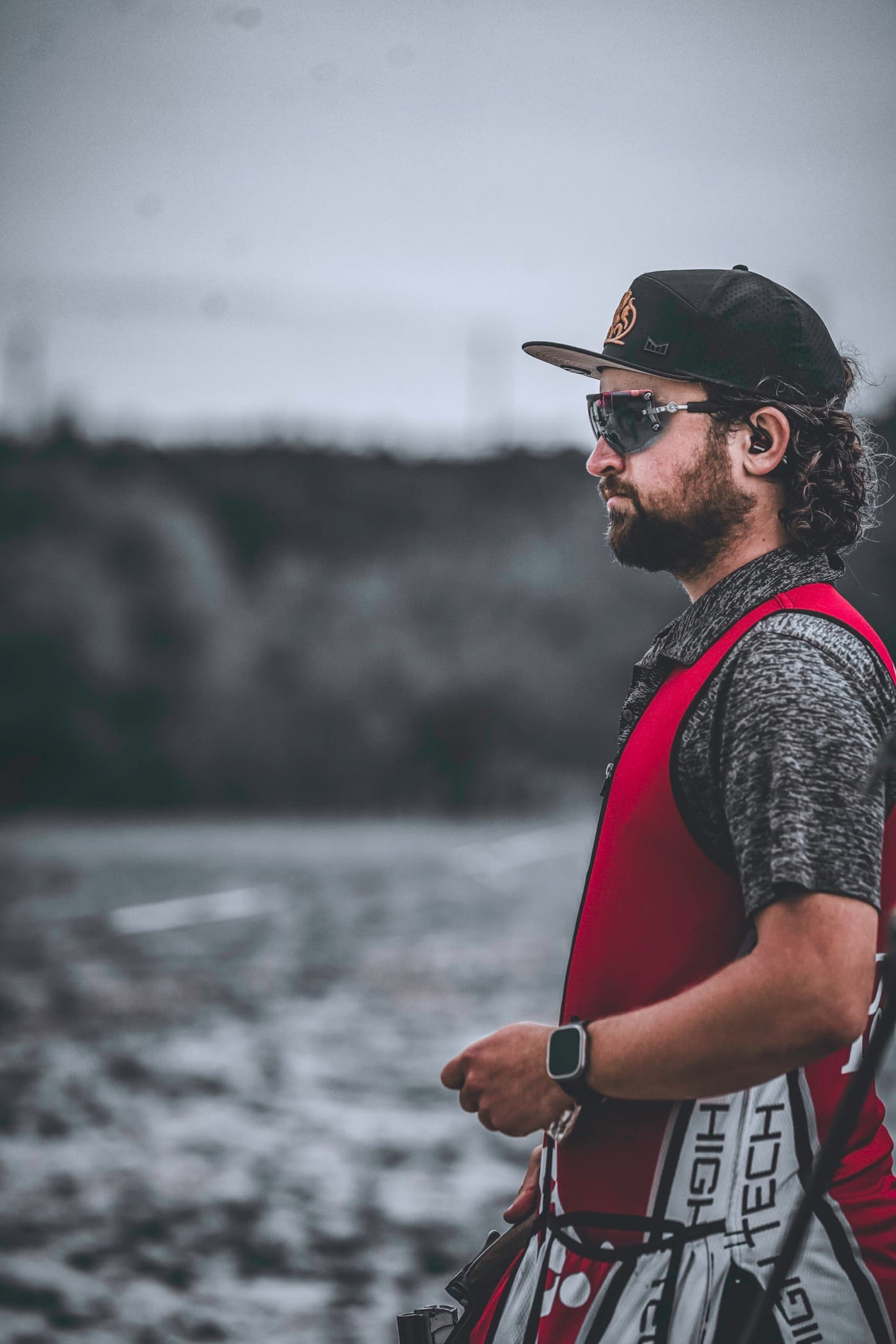 David Radulovich in shooting glasses and a red vest, standing in profile against a muted field.