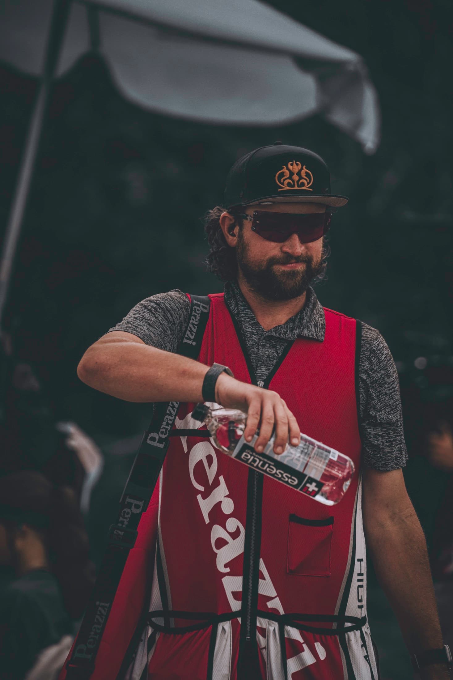 David in a red competition vest pouring water beneath a dark canopy.