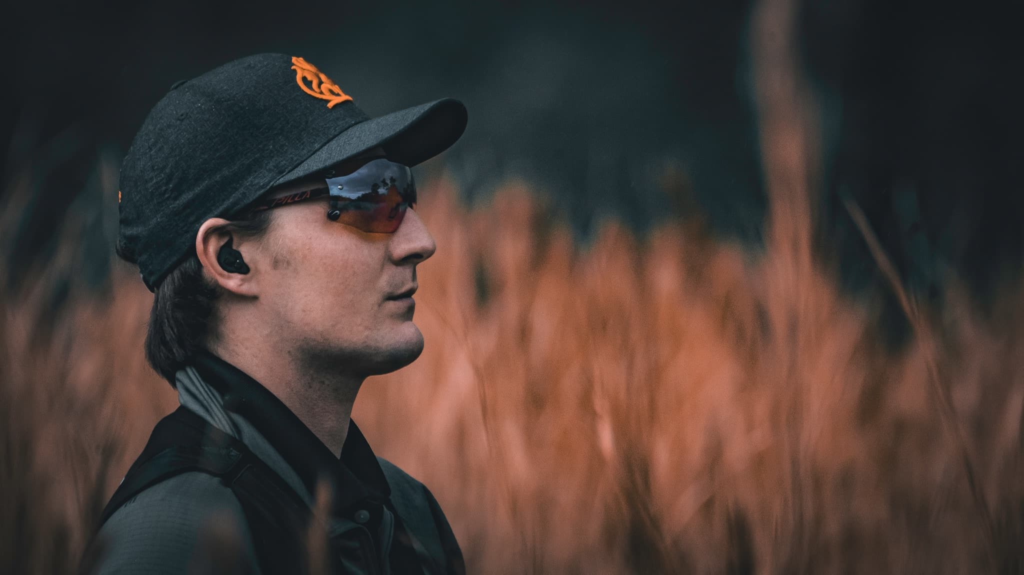 David Radulovich standing in tall grass and watching the field in muted outdoor light