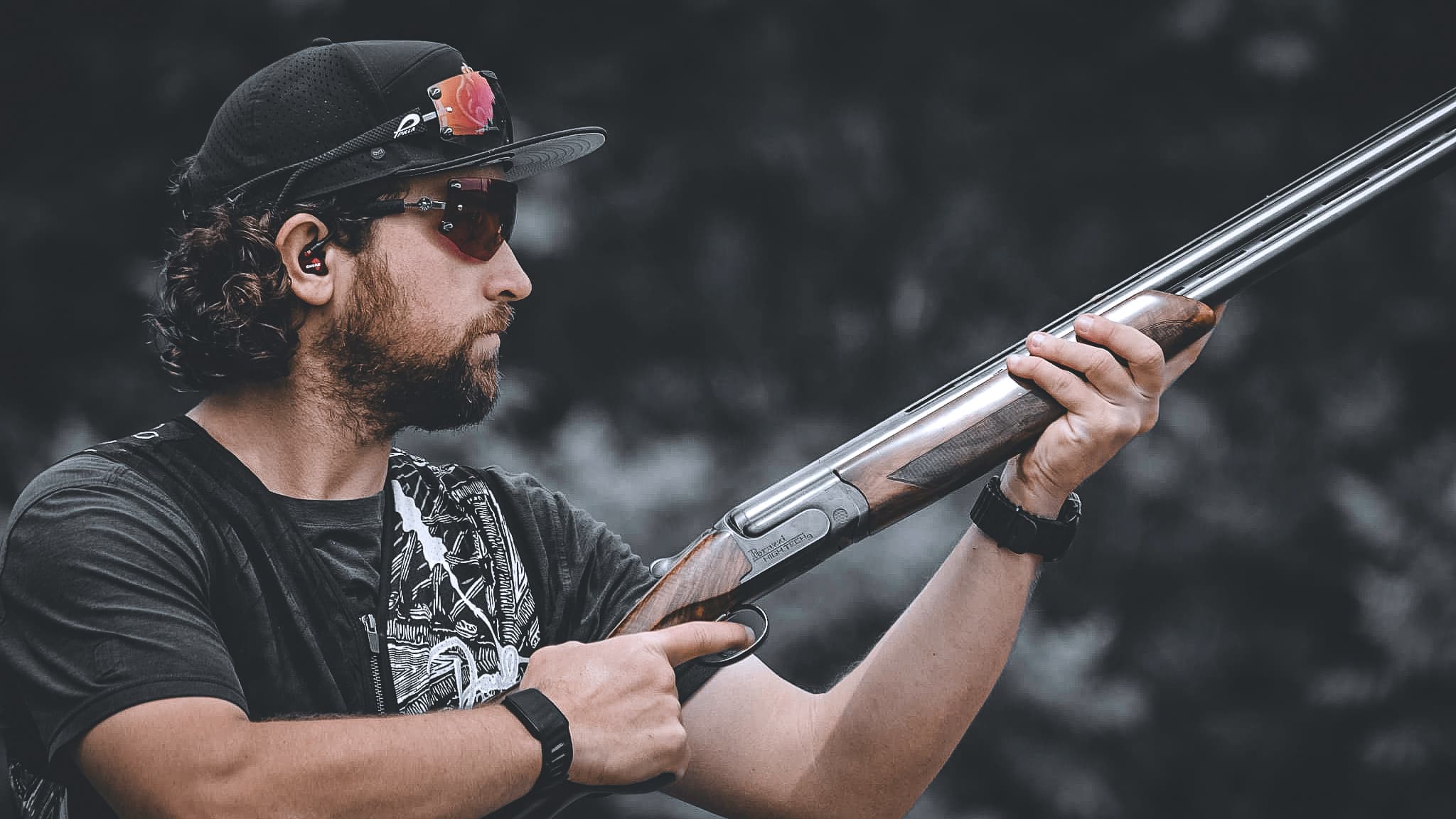 David holding a shotgun in profile against a dark background.