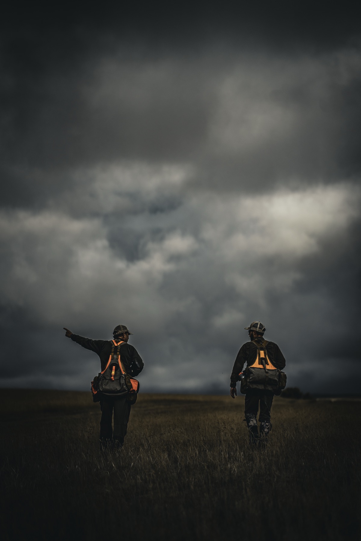Two people walking through open ground beneath a wide sky.
